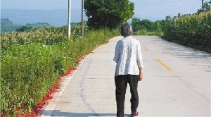 雷政富當年就是走著這條路離開村子的，他75歲的老母親站在路上，路旁是爆竹碎屑，雷的父親剛剛?cè)胪?。黃葆青