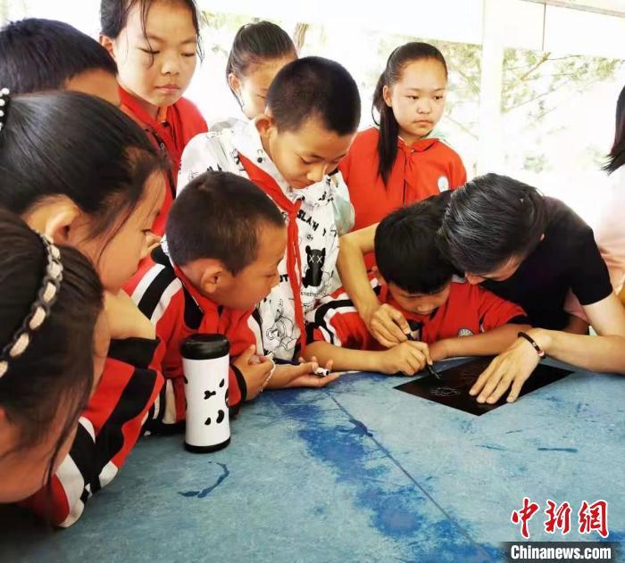 圖為朱增平(右一)教學(xué)生創(chuàng)作鍥金畫(huà)。(資料圖) 受訪者供圖