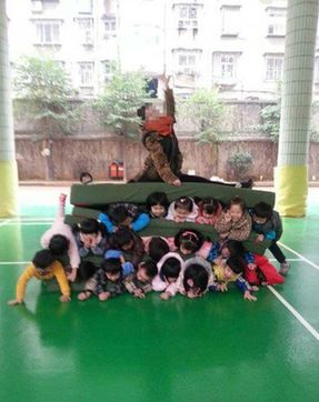 數(shù)名幼兒夾墊子中老師坐上方 園方:鍛煉抗壓能力